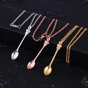 Three crown spoon necklaces in silver, gold, and rose gold on a black jewelry display