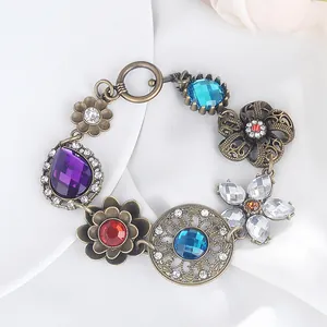 Dettaglio di bracciale boho vintage con cristalli colorati e maglie a fiori in bronzo antico