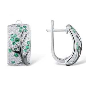 Detail view of silver floral earrings with black branches and green crystals
