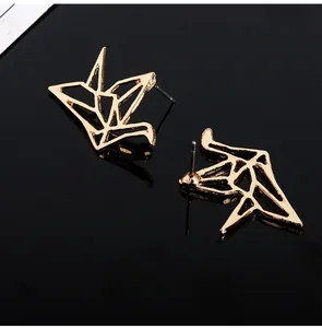 Primer plano de pendientes de grulla de origami dorada con diseño de líneas geométricas