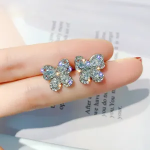 Detailed close-up of crystal butterfly earrings held between fingers for scale