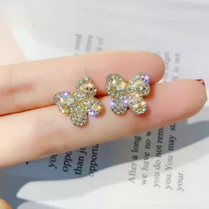 Macro view of butterfly stud earrings with sparkling rhinestones on fingertips