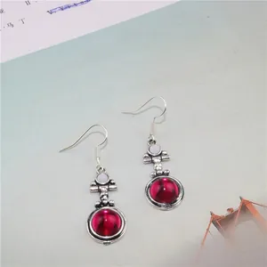 Detail of vintage silver earrings featuring round red gemstones and retro boho style hooks