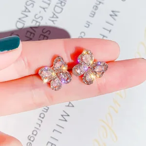Detailed macro view of crystal butterfly stud earrings with sparkling rhinestones on finger