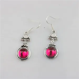 Macro detail of vintage silver drop earrings featuring magenta stones and white accents