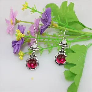 Detail of vintage silver earrings featuring purple crystal teardrop and white resin inlay