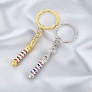 Detalle macro de llaveros de poste de barbero en oro y plata con rayas rojas blancas y azul