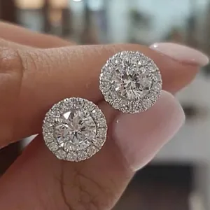 Classic silver halo stud earrings with round cubic zirconia stones held by fingers
