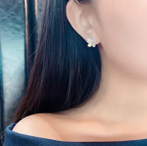 Close-up of elegant butterfly stud earrings with sparkling zircon inlay on earlobe