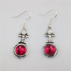 Close-up of vintage drop earrings with red round resin stones and silver alloy hooks