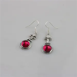Close-up of vintage silver drop earrings with red resin stones and white crystal details