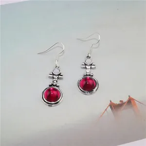 Close-up of vintage drop earrings with large red round stones and silver hooks