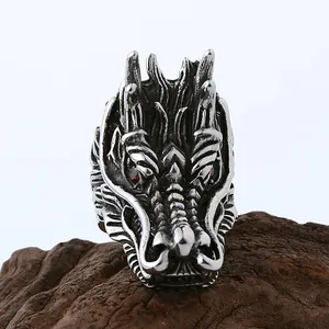 Détail d'une bague dragon rétro en argent avec yeux en zircon rouge sur socle en bois