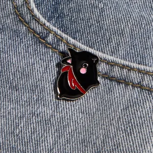 Cute black cat enamel pin with red scarf on denim background for fashion accessories