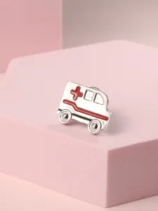 Macro shot of ambulance enamel brooch with red medical cross on pink stand