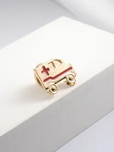 Golden ambulance brooch with red enamel detailing and a secure butterfly clutch back