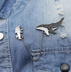 Vue détaillée de l'ensemble broche astronaute et baleine avec chaîne sur une veste en jean
