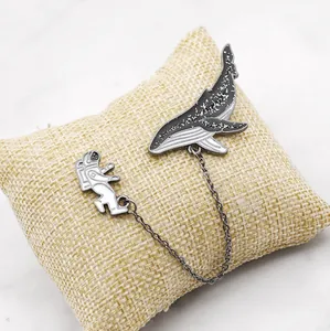 Set de broches émaillées astronaute et baleine avec chaîne sur coussin en lin beige