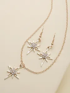 Macro shot of gold starburst jewelry set with sparkling rhinestones on textured background