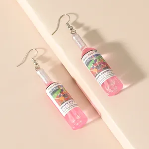 Pink resin wine bottle earrings with glitter detail on beige geometric background