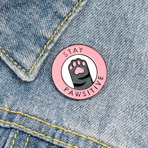 Broche chat rose mignonne avec slogan 'Stay Pawsitive' sur un col de veste en jean