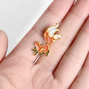 Broche renard en émail orange avec détails dorés et étoiles tenue dans la main