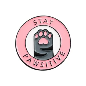 Épingle émaillée ronde Stay Pawsitive avec motif de patte de chat sur fond blanc pur