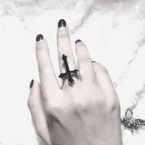 Gothic upside down cross ring in black and silver drip oil finish on a finger