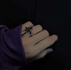 Gothic cross ring with black enamel drip oil finish worn on finger in close-up view