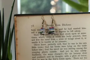 Detailaufnahme der Vintage Buch-Ohrringe, hängend an alten Buchseiten in natürlicher Kulisse