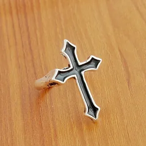 Detail of gothic silver cross ring with black enamel inlay on wood background