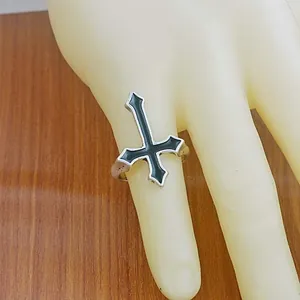 Silver cross ring with black enamel inlay for women on a wooden background