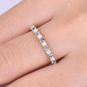 Roségoldener Ring mit weißem Opal und hellblauen Edelsteinen am Finger getragen