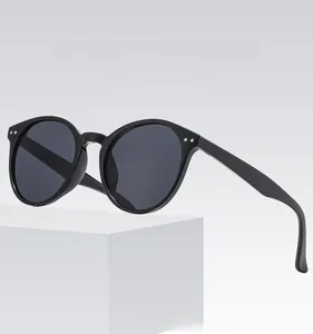 Detail of black round frame sunglasses with silver rivet accents and dark grey lenses