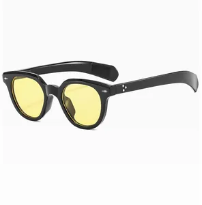 Close-up of retro oval sunglasses with black frame, yellow lenses, and star rivet details