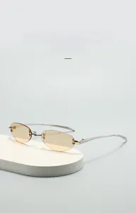 Detail of rimless oval sunglasses with light brown lenses and silver metal temples