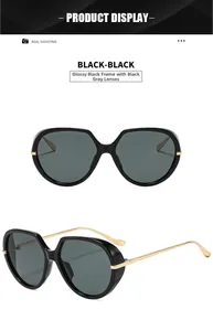 Detail of oversized black polygon sunglasses with thin gold metal temples and gray lenses