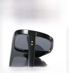 Detail of black aviator sunglasses showing golden hexagonal rivets and glossy frame joints
