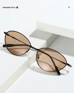 Détail de lunettes de soleil ovales en métal avec verres ambrés sur socle minimaliste