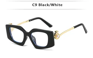 Detail of square black frame glasses featuring gold metal temples and pearl accents
