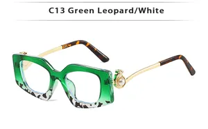 Detail of square glasses featuring gold leopard head hinge and pearl accents