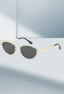Gros plan détaillé de lunettes de soleil ovales en métal doré avec verres gris foncé