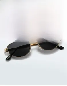 Détail de lunettes de soleil ovales en métal doré avec verres gris foncé au style rétro