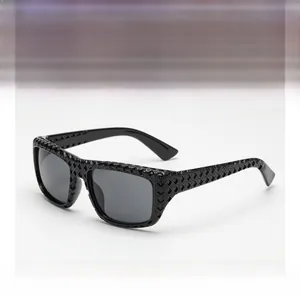Détail de lunettes de soleil noires avec motif ajouré en losange 3D sur la monture