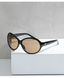 Detail view of oversized black square sunglasses with brown lenses on a white pedestal