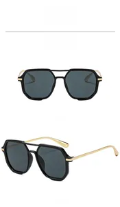 Detail of square sunglasses with black frames, gray lenses, and golden metal temples