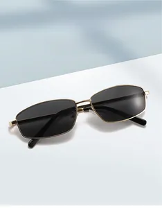 Detail of square gold metal sunglasses with dark gray lenses and refined frame texture