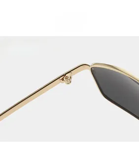 Macro detail of the sturdy golden metal hinge and sleek grey lens of Y2K square sunglasses