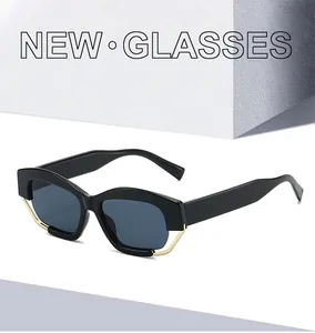 Detail der geometrischen Cat-Eye-Brille mit Golddrahtbesatz und dunklen Gläsern