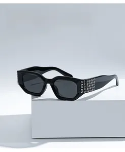 Détail de lunettes de soleil hexagonales noires avec clous en métal argenté sur les branches